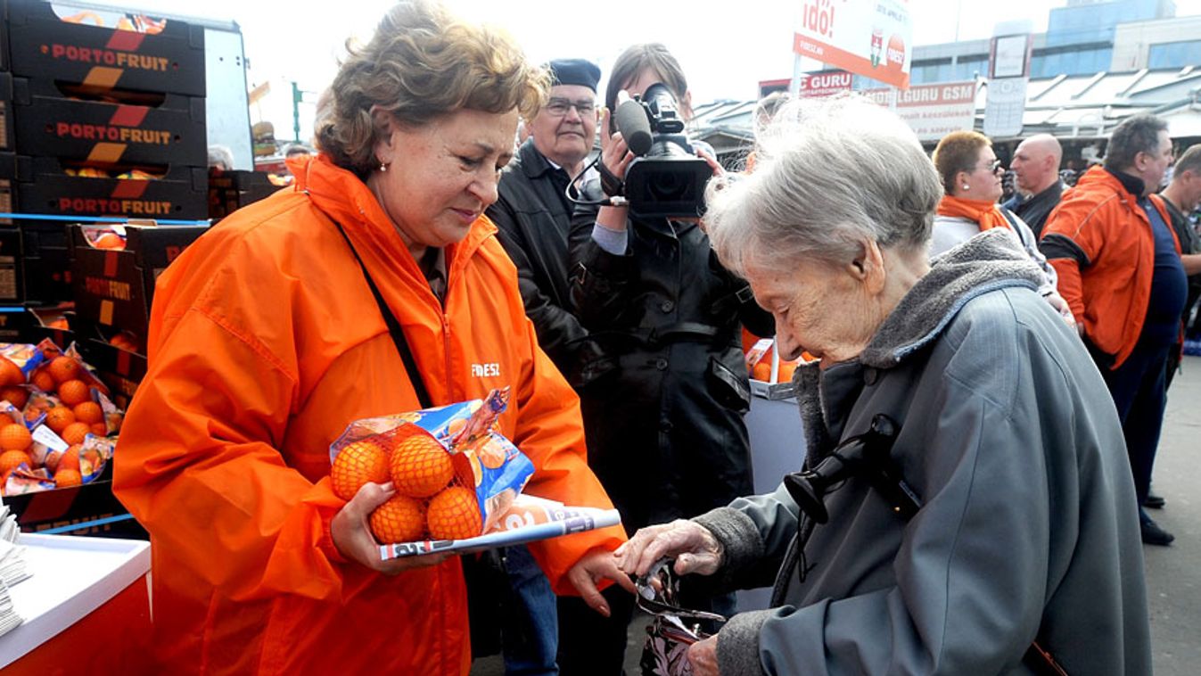 fidesz aktivisták, fidesz, kampány 2010, önkéntes,  Aktivista narancsot ad egy idős nőnek Budapesten az Örs vezér terén, a Fidesz kampányrendezvényén.