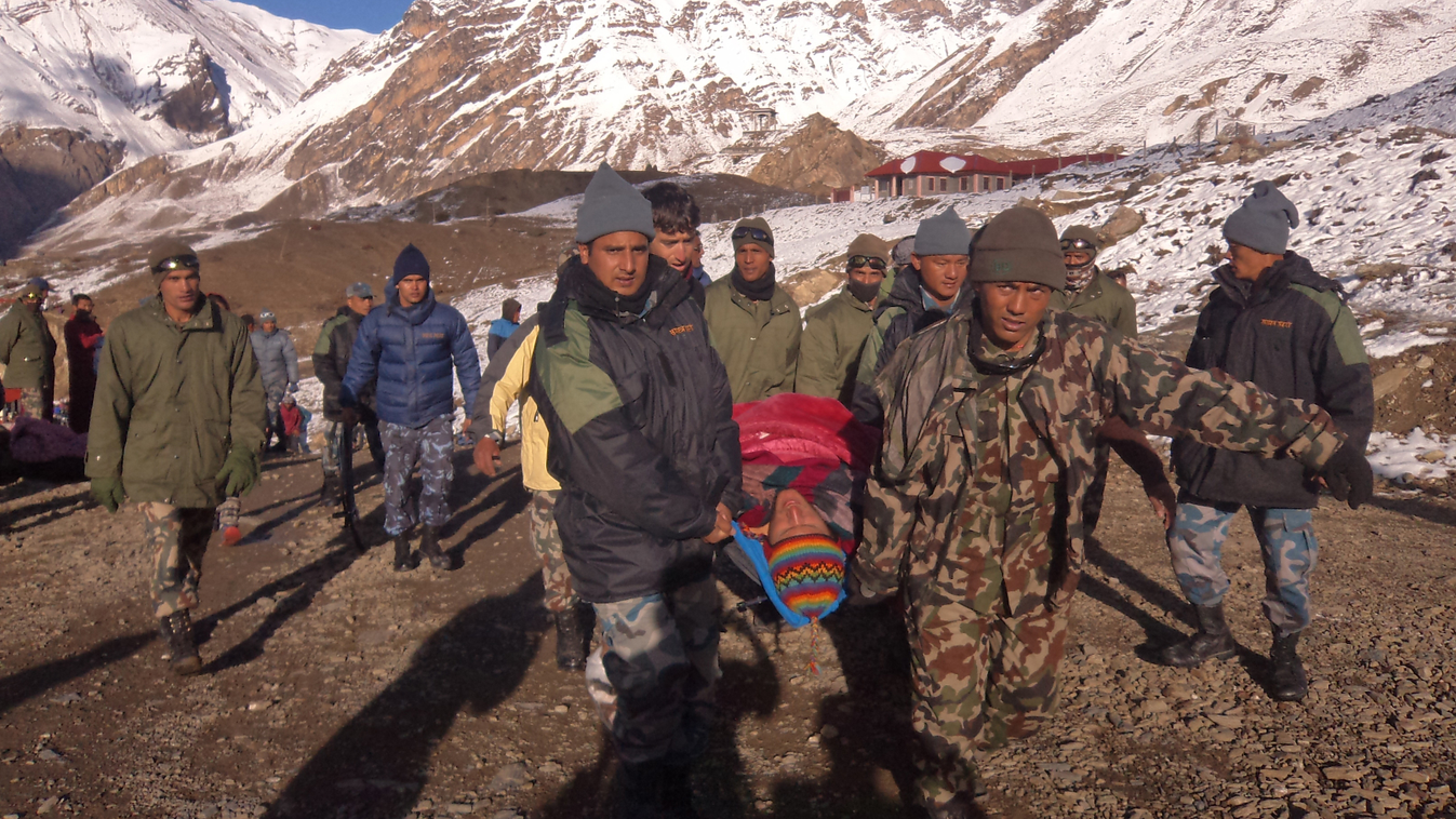 In this handout photograph released by the Nepal Army on October 15, 2014, an injured survivor of a snow storm is assisted by Nepal Army personel in Manang District, along the Annapurna Circuit Trek.  A snowstorm and avalanche in Nepal's Himalayas has kil