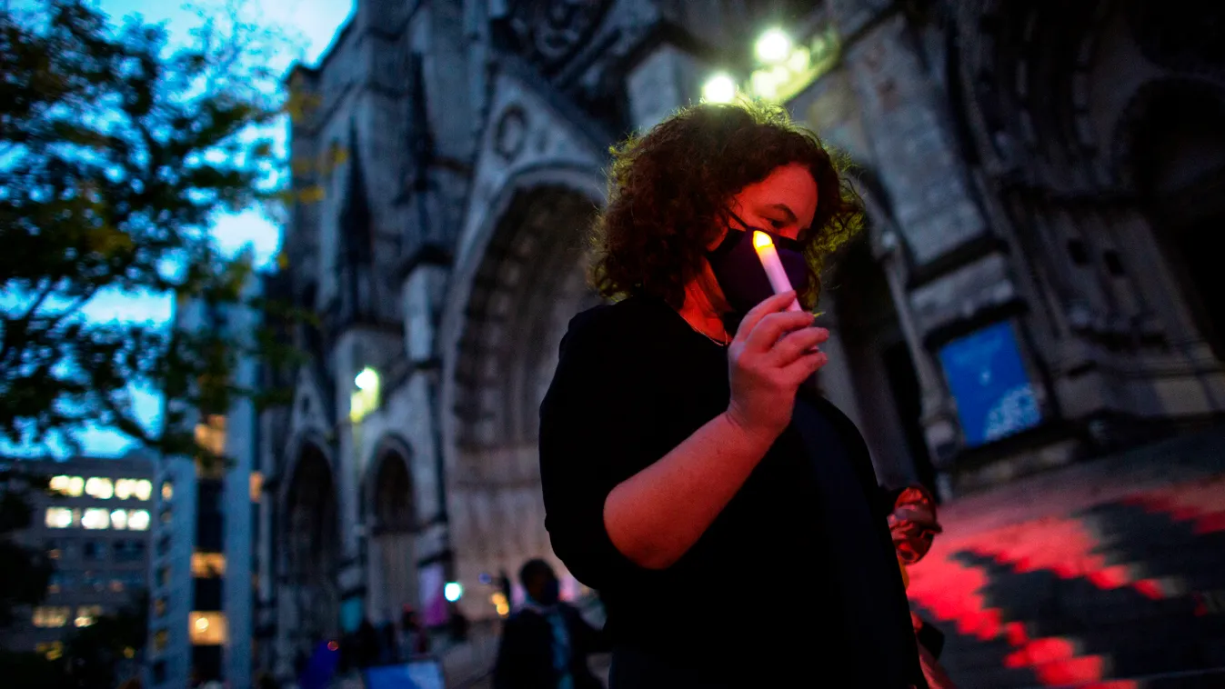 health virus pandemic Horizontal A woman attends a candlelight vigil a procession in tribute to all of the lives affected by the novel coronavirus outside The Cathedral of St. John the Divine on October 19, 2020, in New York City. (Photo by Kena Betancur 
