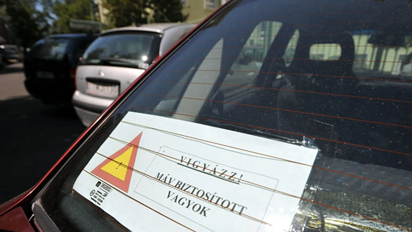 .
Egy óvatos autós szélvédőjére rakott felirat: Vigyázz! MÁV biztosított vagyok!, ILLUSZTRÁCIÓ a MÁV ÁBE, biztosító egyesület kártalanítási perhez
