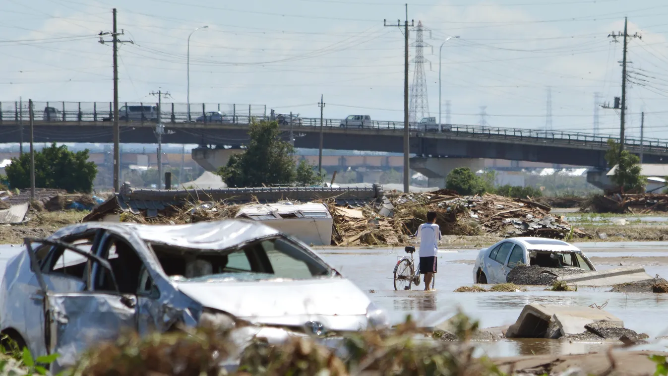 A man pushes his bicycle past stranded vehicles in muddy water in the city of Joso in Ibaraki prefecture on September 11, 2015. Thousands of rescuers arrived in a deluged city north of Tokyo on September 11 to help evacuate hundreds of trapped residents a