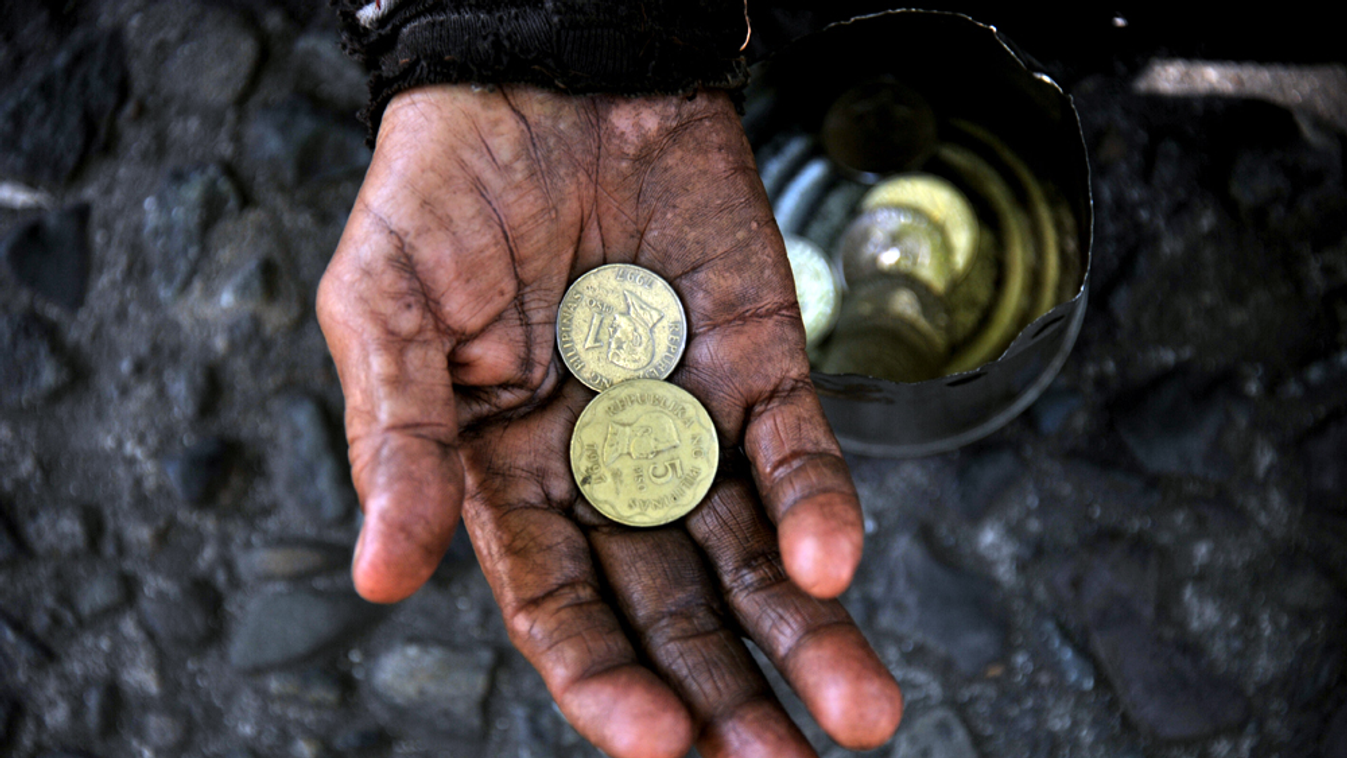 Szegénység POVERTY A woman holds coins in her hand as she begs for money from passers-by on a street near the Malacanang palace in Manila on March 1, 2012. One in four Filipinos live on a dollar a day or less, according to a governm 