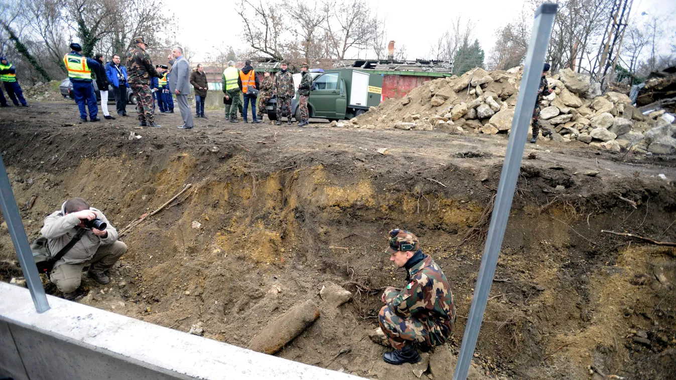 Budapest, 2015. január 20.
Egy tűzszerész és egy fotós a XIV. kerületi Vágány utca elején végzett földmunkák során talált tüzérségi lövedék mellett 2015. január 20-án. A rendőrség lezárta a környéket.
MTI Fotó: Mihádák Zoltán 