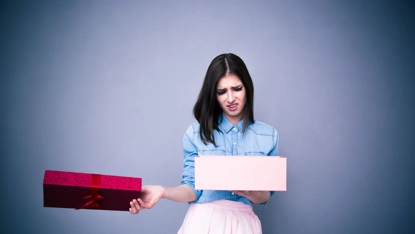 Dissatisfied woman opening gift Beautiful Women Celebration Facial Expression Anniversary Adult Frowning Holding Receiving Backgrounds Caucasian Ethnicity Frustration Sadness Rudeness Disappointment Displeased Human Face Brown Hair People Gift Christmas B