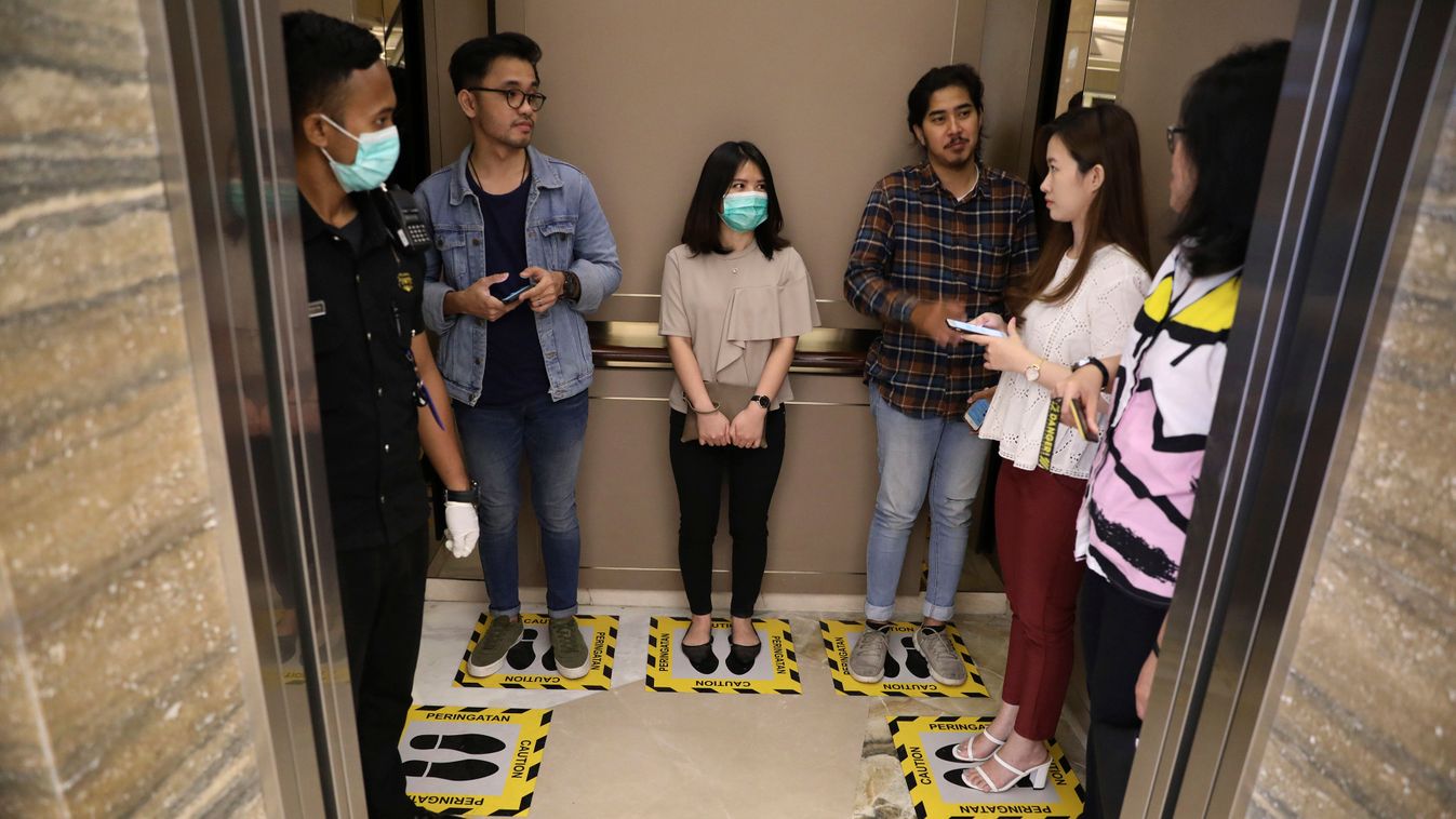 Surabaya, 2020. március 19.
Az új koronavírus járványa elleni védekezésül felfestett helyeken állnak egy lift utasai az indonéziai Surabaya egyik bevásárlóközpontjában 2020. március 19-én. A jelölések az utasok közötti megfelelő távolságot szabják meg, am