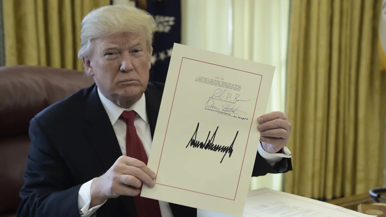 TOPSHOTS Horizontal PRESIDENT SIGNING OF AN AGREEMENT REFORM ECONOMY WHITE HOUSE DOCUMENT United States President Donald J. Trump holds up a document during an event to sign the Tax Cut and Reform Bill in the Oval Office at The White House in Washington, 