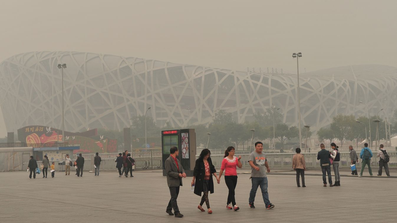This picture taken on October 9, 2014 shows people walking past the Bird Nest, or the National stadium in Beijing amid heavy smog. Days of heavy smog shrouding swathes of northern China pushed pollution to more than 20 times safe levels, despite governmen