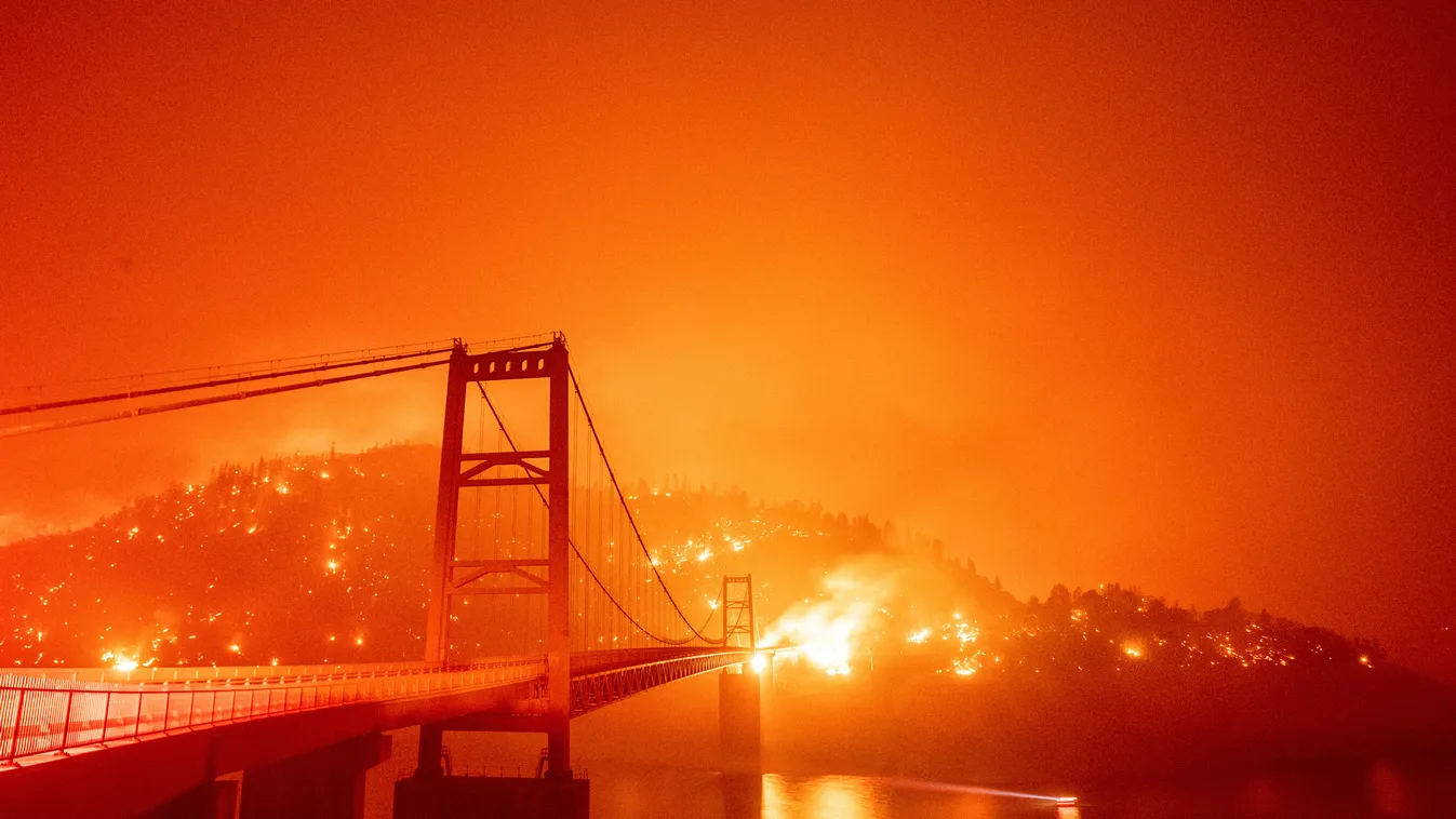 TOPSHOTS Horizontal FIRE BRIDGE A boat motors by as the Bidwell Bar Bridge is surrounded by fire in Lake Oroville during the Bear fire in Oroville, California on September 9, 2020. - Dangerous dry winds whipped up California's record-breaking wildfires an