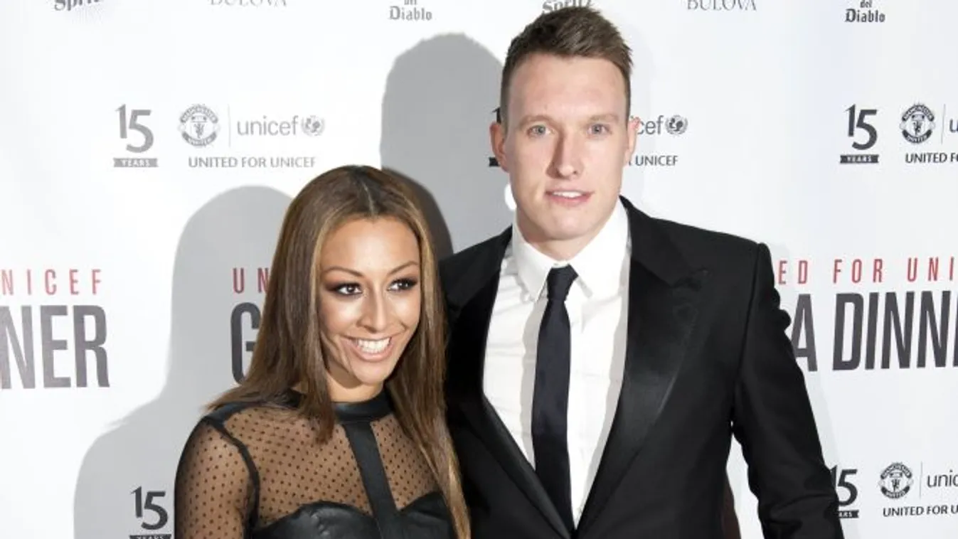 Manchester United's English defender Phil Jones and his partner Kaya Hall pose for pictures on the red carpet as they arrive to attend the "United for UNICEF" Gala Dinner at Old Trafford in Manchester, Northern England, on November 4, 2014.   AFP PHOTO / 