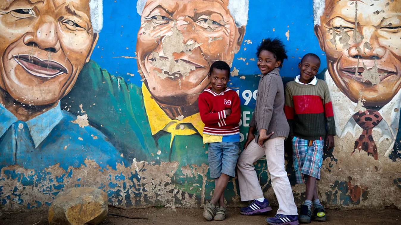 a hét képei, gyerekek állnak egy falfestmény előtt Soweto városban, ami a súlyos beteg, korábbi dél-afrikai elnököt, Nelson Mandelát ábrázolja