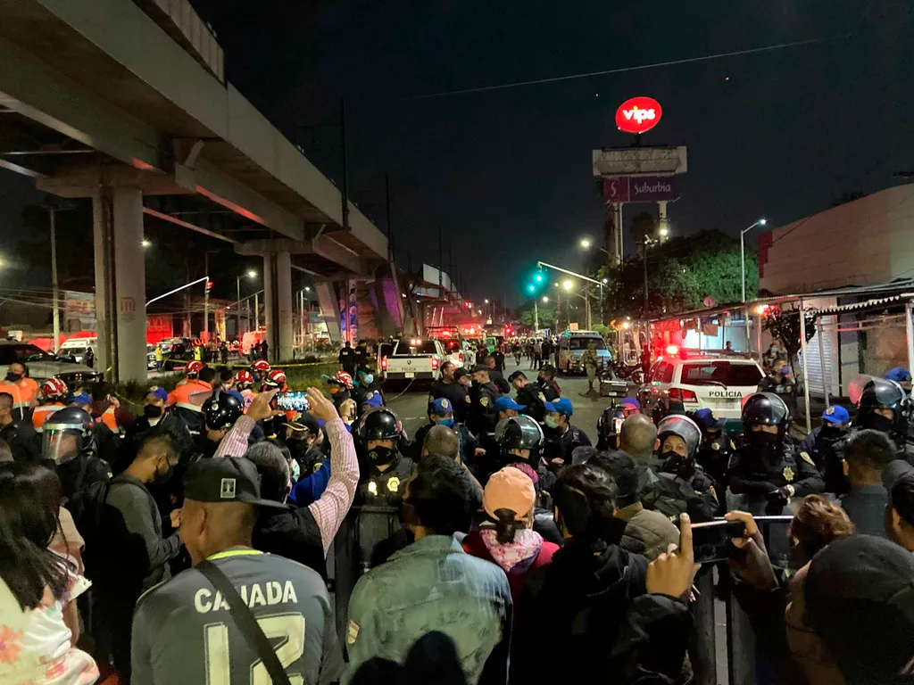 Mexikóváros, 2021. május 4.
Rendőrök riportereket tartóztatnak fel a helyszín közelében, miután leomlott egy metróvonal utcai felüljárója és kocsik zuhantak le Mexikóvárosban 2021. május 3-án este. Legalább tizenhárom ember életét vesztette, mintegy hetve