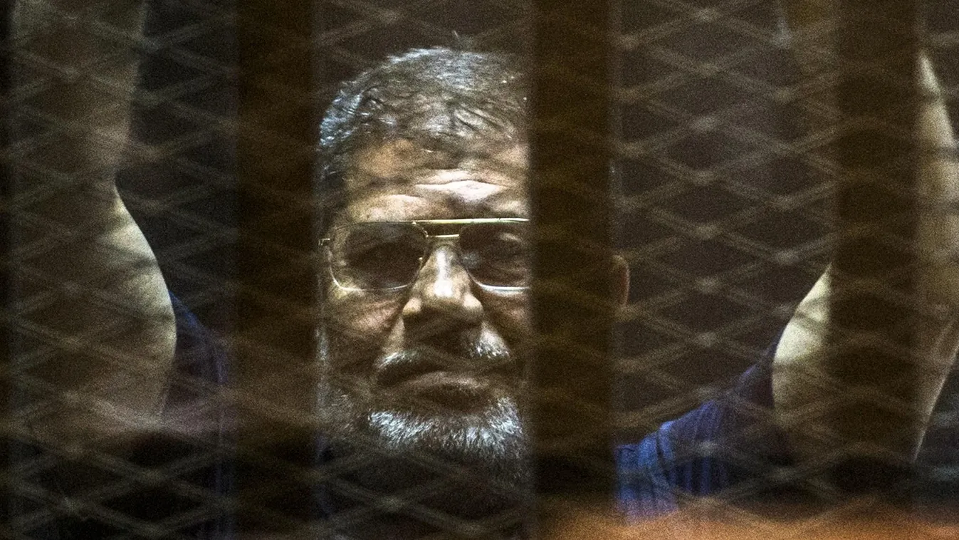 Ousted Egyptian president Mohamed Morsi gestures from the defendants cage as he attends his trial at the police academy on the outskirts of the capital Cairo on June 2, 2015. The Egyptian court postponed its final ruling on Morsi, who was sentenced to dea