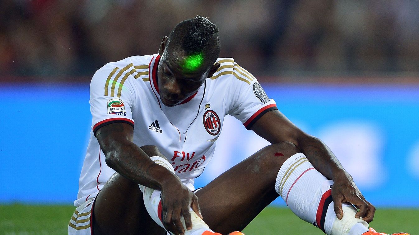 A green light is seen on the head of AC Milan's forward Mario Balotelli as he reacts during the Italian Serie A football match between AS Roma and AC Milan on April 25, 2014 at the Olympic stadium in Rome.    AFP PHOTO / FILIPPO MONTEFORTE 