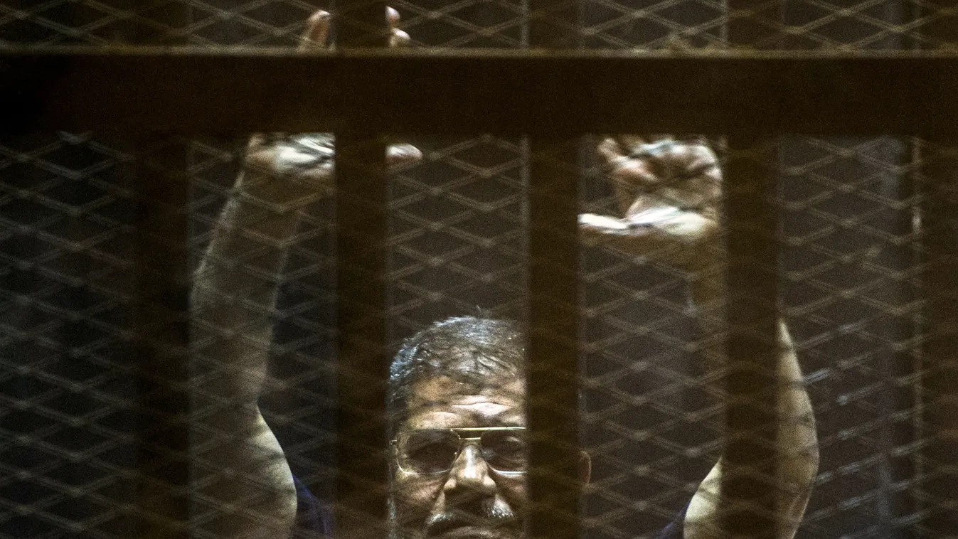Ousted Egyptian president Mohamed Morsi gestures from the defendants cage as he attends his trial at the police academy on the outskirts of the capital Cairo on June 2, 2015. The Egyptian court postponed its final ruling on Morsi, who was sentenced to dea