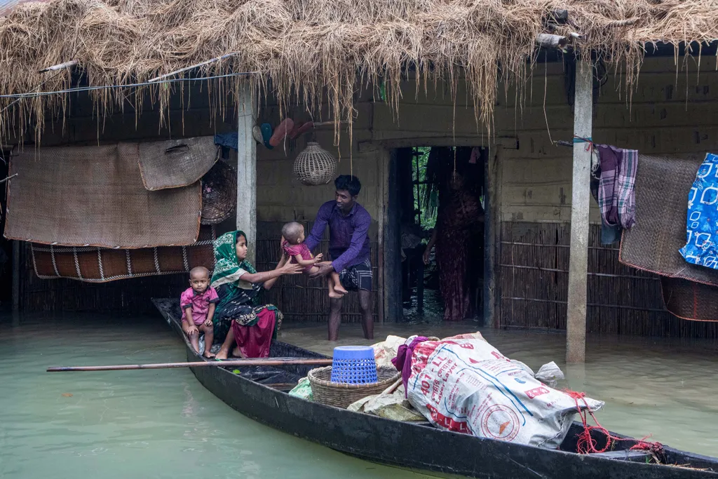 bangladeshi árviz  flood weather Horizontal A woman holds her child as they evacuate their house submerged in a flooded area following heavy monsoon rainfalls in Goyainghat on June 19, 2022. (Photo by AFP) 