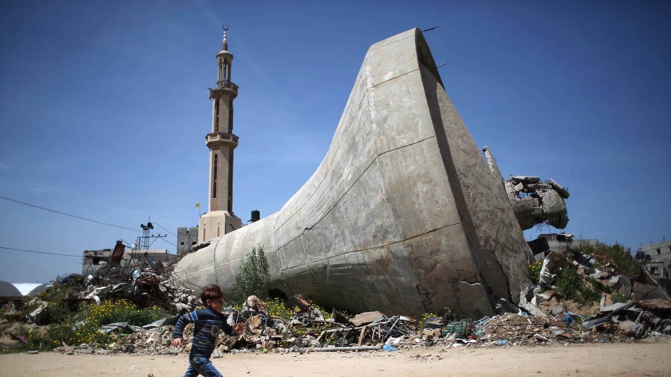 A Palestinian child runs past a water tank that was destroyed in Israeli bombing during the 50-day war between Israel and Hamas militants in the summer of 2014, in the village of Khuzaa, east of Khan Yunis, in the southern Gaza Strip on March 26, 2015. AF