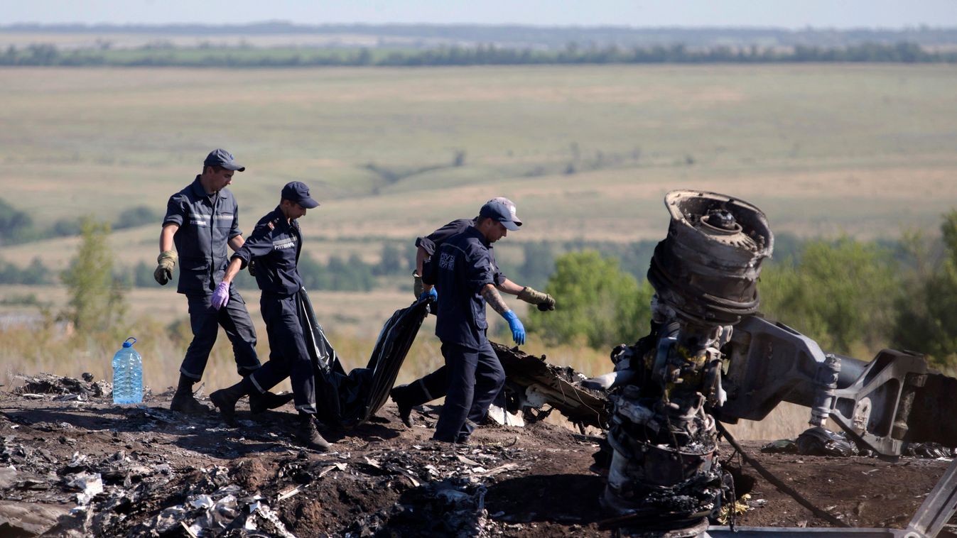 maláj repülőgép egyik áldozatának holttestét viszik egy mentőcsapat tagjai 