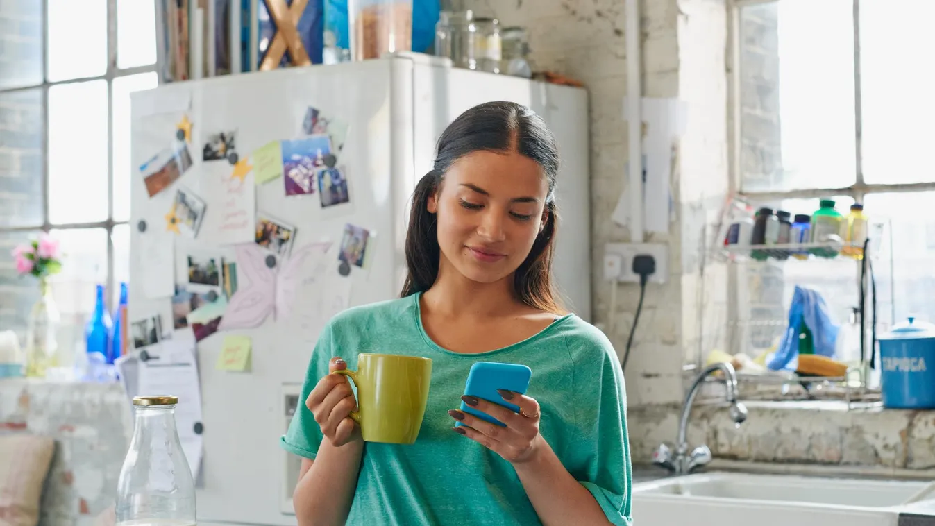 Hispanic girl holding coffee using blue mobile phone at home Smart Phone Beautiful Wireless Technology Morning Text Messaging Women Females Cute Message Young Adult Adult Smiling Holding Intelligence Beauty Latin American and Hispanic Ethnicity One Person