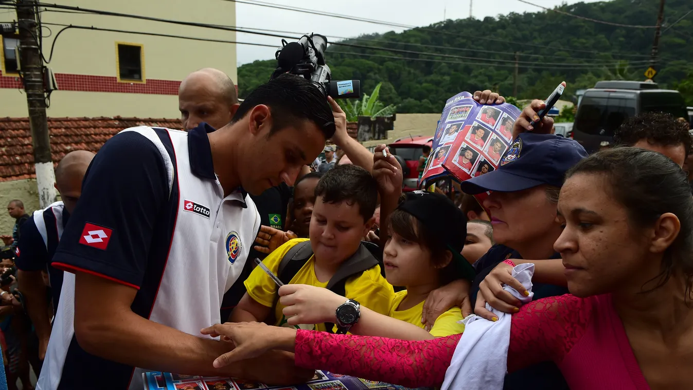 Costa Rica's goalkeeper Keylor Navas (L) signs autographs for Brazilian fans as Costa Rica's national football team visits the "Padre Lucio Floro" school in the Jose Menino neighborhood in Santos, Sao Paulo state, on June 16, 2014, during the FIFA Footbal