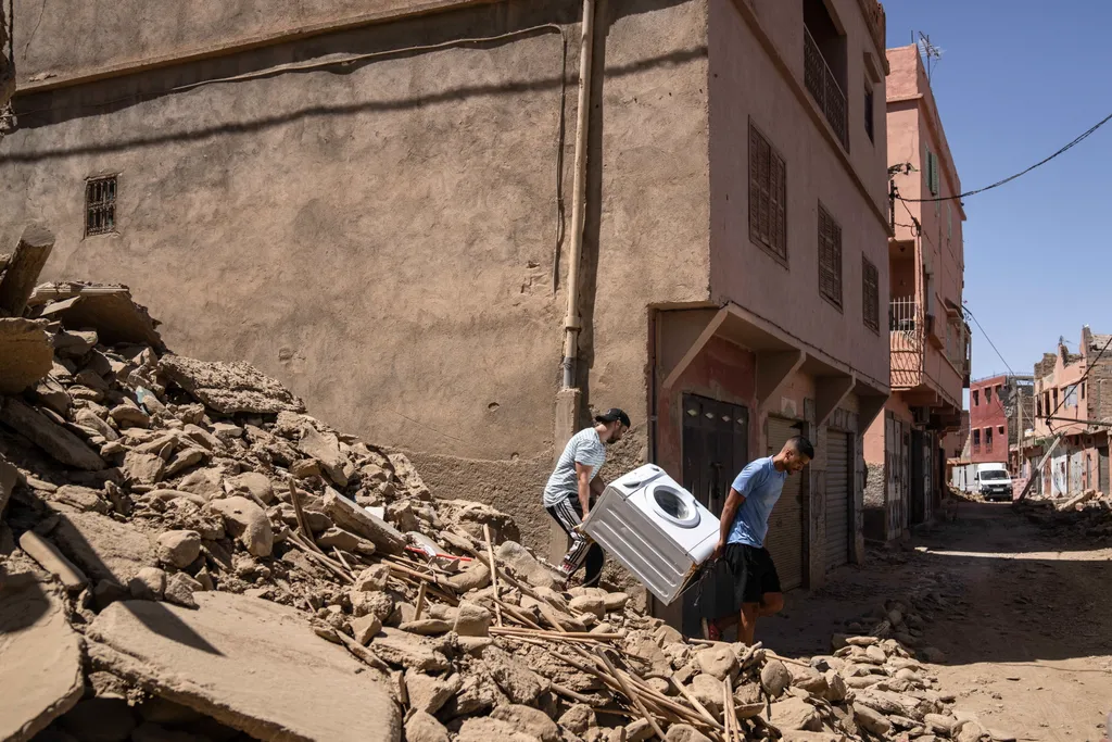 Marokkó földrengés, Észak-Afrika, 2023.09.12. kiszerelt mosógépet cipelnek férfiak a földrengés sújtotta marokkói Azizmiz településen, Marrákestől délre 2023. szeptember 10-én. A szeptember 9-re virradó éjjelen pusztító, 7-es erősségű földmozgá 