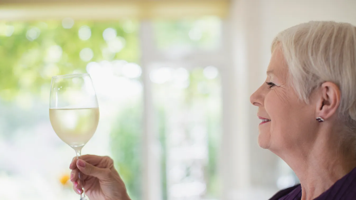 Senior woman drinking white wine senior female chardonnay riesling pinot blanc gris sauvignon Caucasian hair short side smile happy enjoy domestic home leisure lifestyle hold look taste retirement boomer authentic weekend savour connoisseur sensory examin