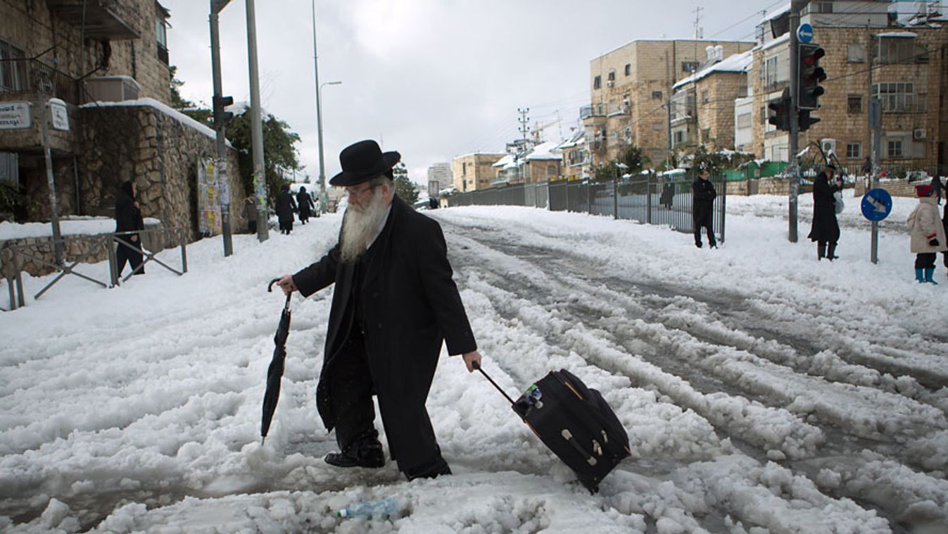 Hó, Izrael. Ultraortodox zsidó férfi kel át az úttesten a hóviharban megbénult Jeruzsálem városában, 2013. december 13.