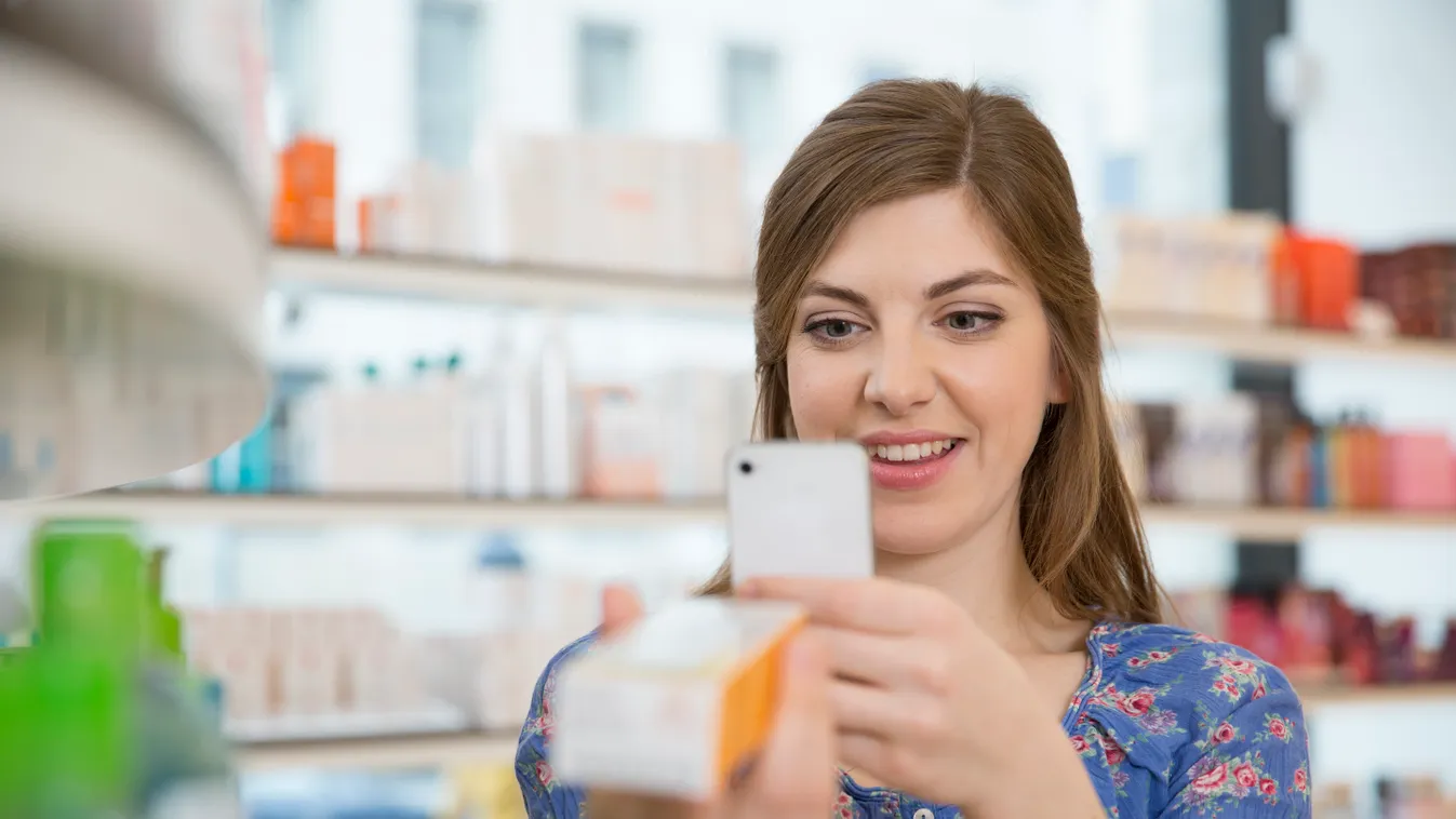 Portrait of woman comparing products in a pharmacy box healthcare and medicine pharmaceutics drugs shelf holding smiling content product on-line Connection choice Beauty Cosmetics service pharmacy trade retail shop front view indoor day Head and shoulders
