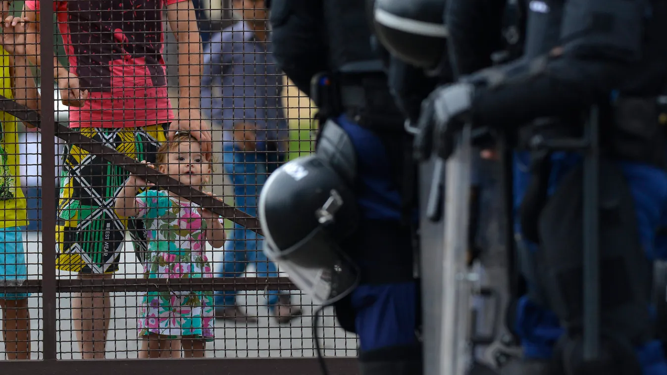 Debrecen, 2015. június 29.
A debreceni migrációs tábor lakói nézik a tábor bejáratánál felsorakozó rendőröket 2015. június 29-én. A környékbeliek elmondása szerint a tábor mintegy száz lakója autókat rongált meg és kukákat gyújtott fel. A táborlakók kiabá