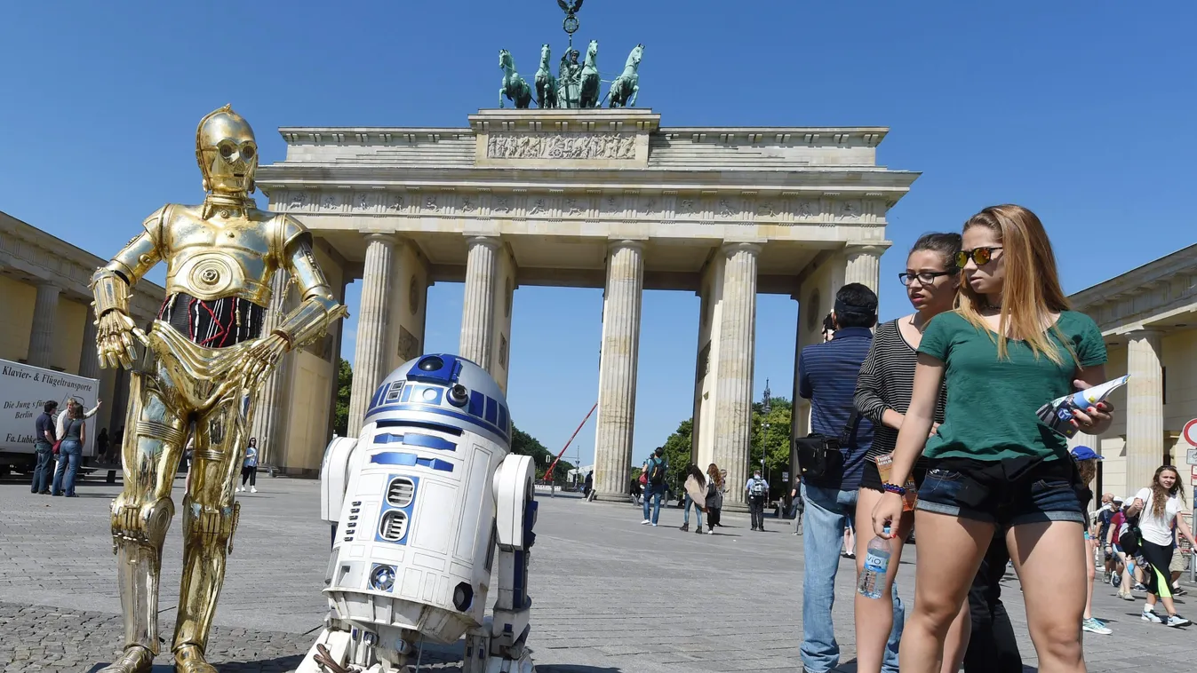 Járókelők nézik a Csillagok háborúja című mozifilmsorozat C-3PO és R2-D2  nevű szereplőinek viaszfiguráit a Brandenburgi kapu előtt Berlinben. A Madame Tussauds Berlin panoptikum időszaki kiállítást nyitott Csillagok háborúja címmel, melynek keretein belü