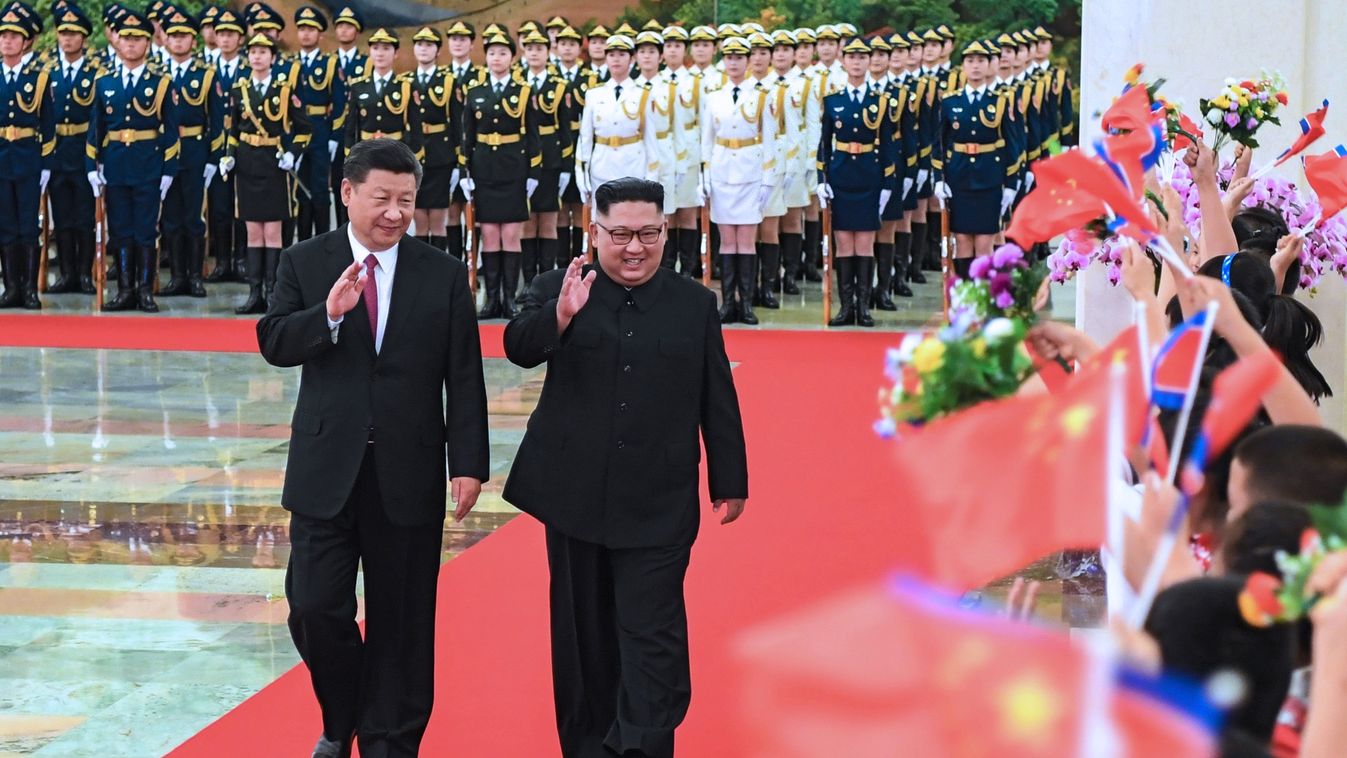 diplomacy politics TOPSHOTS Horizontal This photograph released on June 19, 2018 by China's Xinhua News Agency, shows North Korean leader Kim Jong Un (R) and Chinese President Xi Jinping (L) waving to children after reviewing an honour guard during a welc