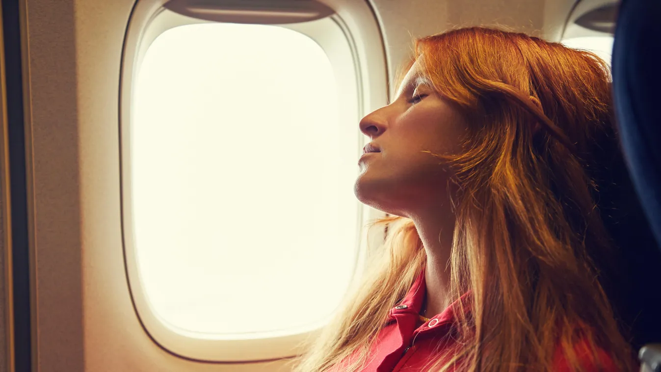 alvó nő repülőn ablaknál 
