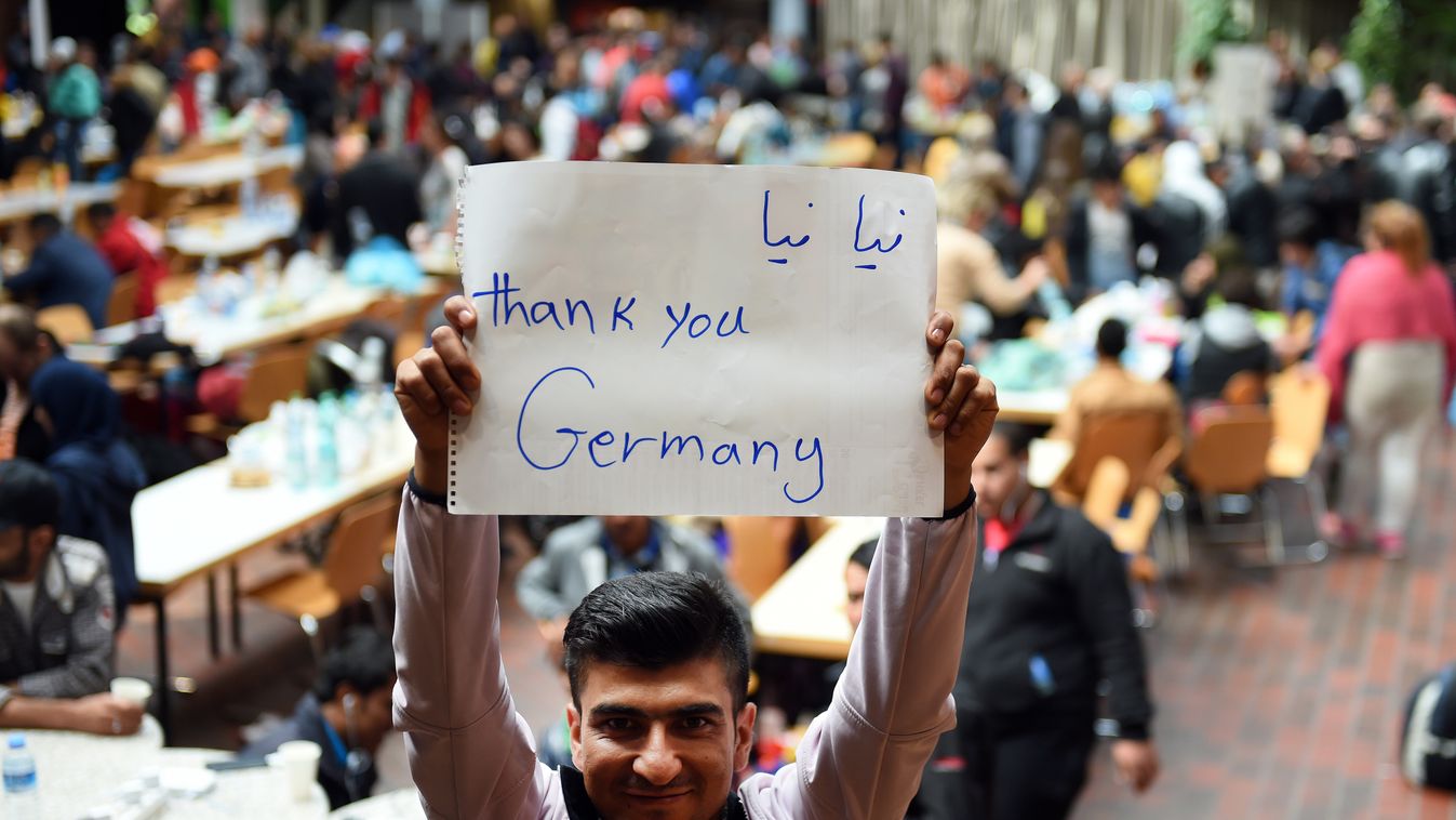 Migrant holds a paper written "Thank you Germany" while waiting for a bus after his arrival at the train station in Dortmund, western Germany, on September 6, 2015. Over 1,000 more migrants arrived in Germany to cheers and "welcome" signs, but calls grew 