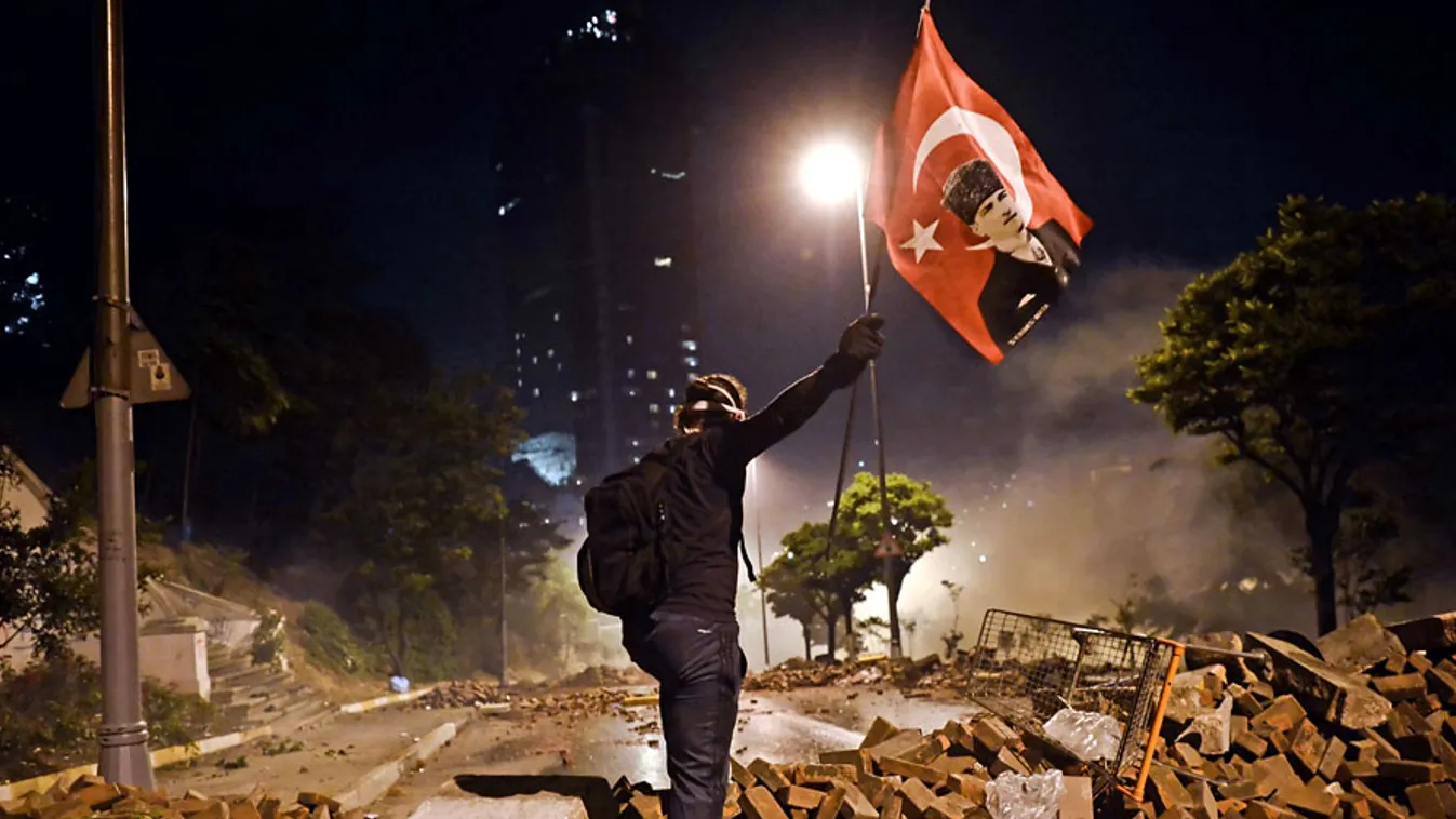  Törökország, kormányellenes tüntetések, török tüntetések, A világi Török Köztársaság alapítóját, Mustafa Kemal Atatürköt ábrálózó nemzeti zászlót lenget egy tüntető egy barikádon Taksim és Besiktas városrészek között, Isztambulban, 2013. június 3-án