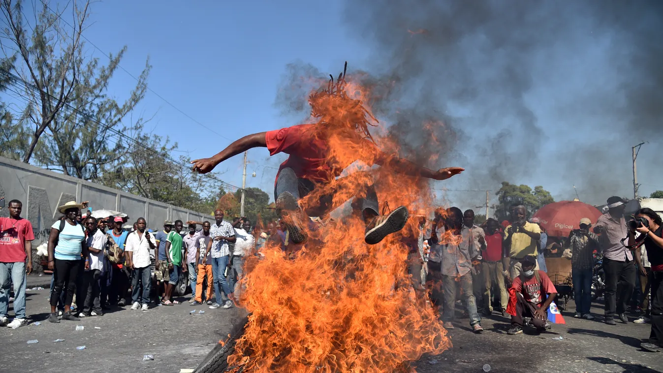 Tüntetők autógumikat égetnek és átugrálnak a lángokon a haiti ellenzéki pártok demonstrációján Port-au-Prince-ben. A kormányzó pártot választási csalással vádoló tiltakozók a haiti választások január 24-re kiírt második fordulójának elhalasztását követeli