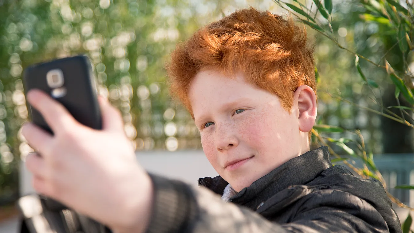 Boy using smartphone to take a selfie wireless technology social media posing selfie autofoto only children only boys one boy only preteen boy one person 10-11 years pre-adolescent child confidence connection narcissism wireless device smartphone casual c