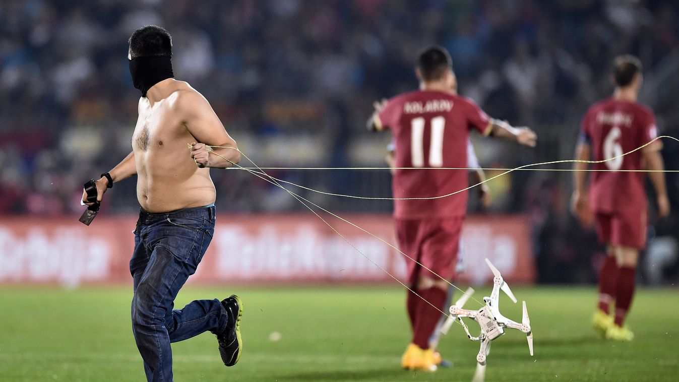 510260445 A masked Serbian supporter pulls a drone, after a flag with Albanian national symbols has been flown into the stadium, during the Euro 2016 group I football match between Serbia and Albania in Belgrade on October 14, 2014.   AFP PHOTO / ANDREJ I