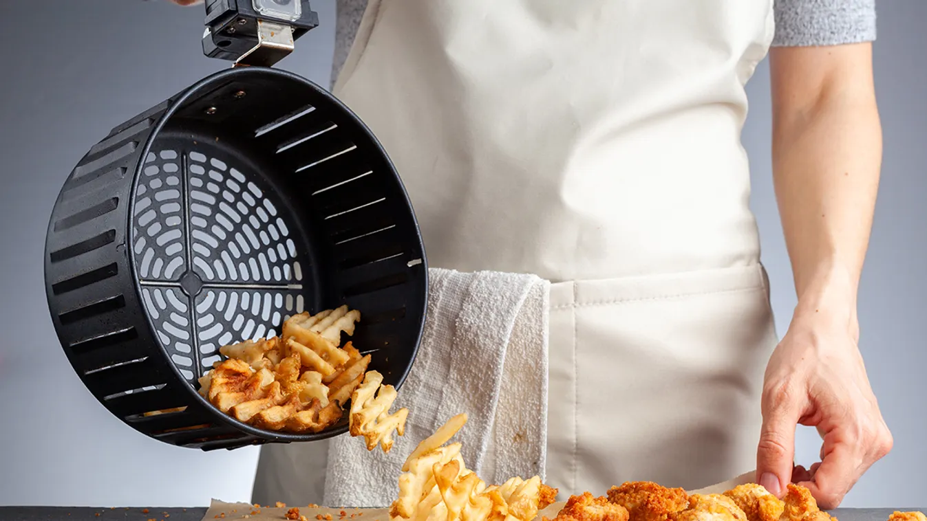 A,Woman,Is,Dumping,Fresh,Made,Potato,Waffle,Fries,From A woman is dumping fresh made potato waffle fries from basket onto a countertop together with chicken nuggets. She fried them in air fryer using very little fat. A healthy homemade convenient snack. 