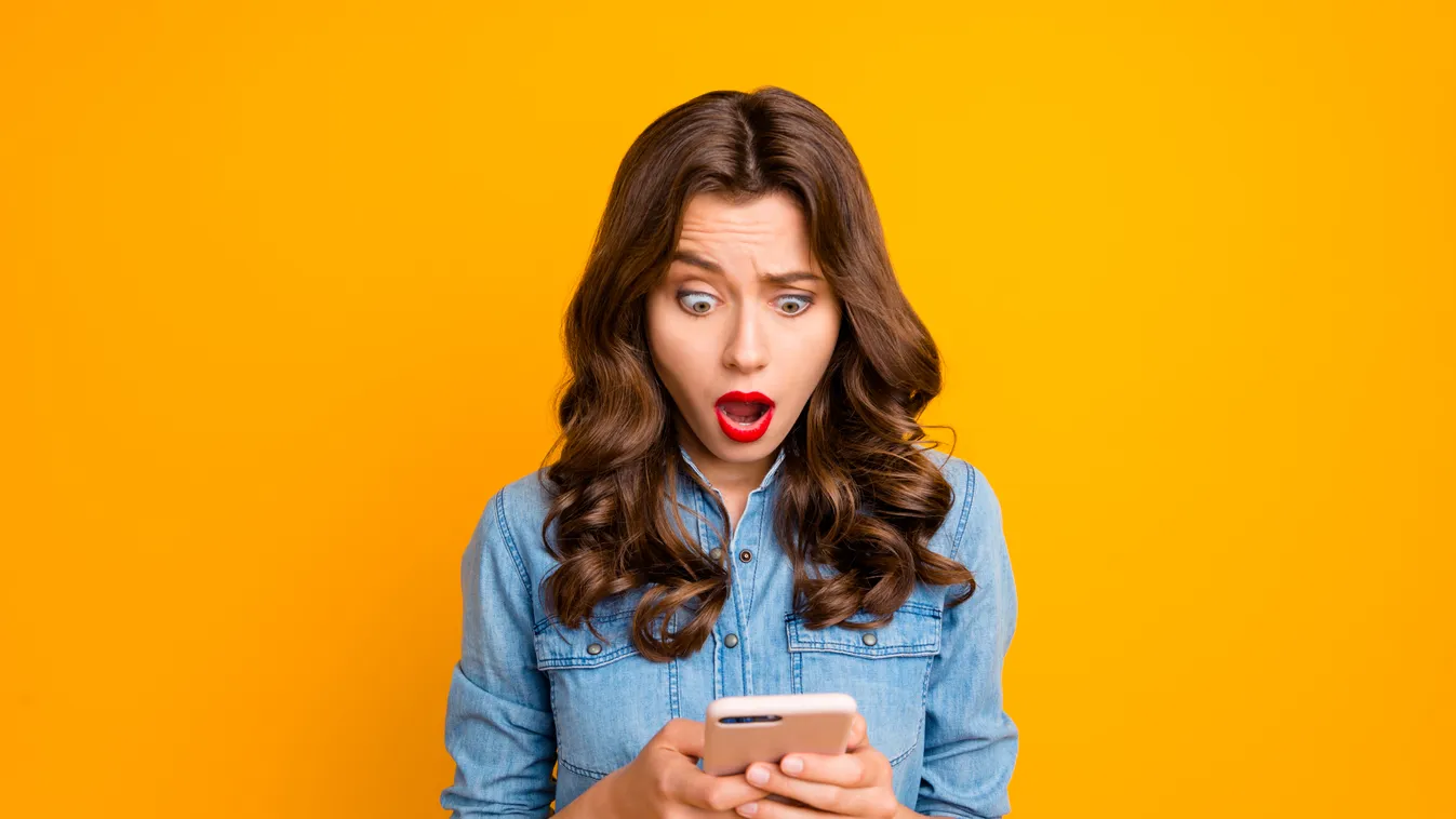 Photo of curly wavy cute brunette nice charming casual girl having seen disappointing message on her phone with terrified facial expression isolated over vivid color background afraid amazed astonished browsing cell cellphone chatting denim disappointed f