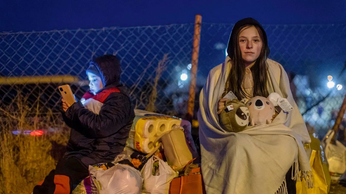 Gyermek menekültek  TOPSHOTS Horizontal UKRAINE CRISIS REFUGEE WOMAN CHILD MOBILE PHONE NIGHT Helena (R) and her brother Bodia (L) from Lviv are seen at the Medyka pedestrian border crossing, in eastern Poland on February 26, 2022, following the 