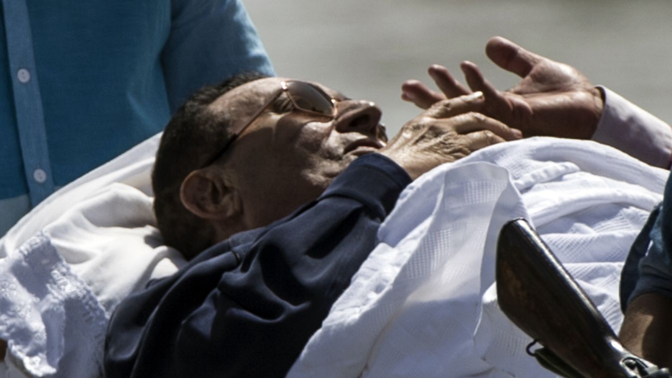 Former Egyptian president Hosni Mubarak speaks to a member of his aid as he is wheeled out of a helicopter into an ambulance outside the Maadi military hospital in Cairo on September 27, 2014 after returning from the court. An Egyptian court postponed its