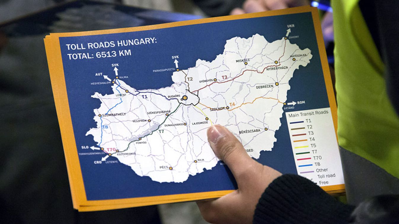 Az Állami Autópálya Kezelő Zrt. egyik munkatársa szórólappal segít a kamionsofőröknek az e-útdíj intézésében a letenyei határátkelőn