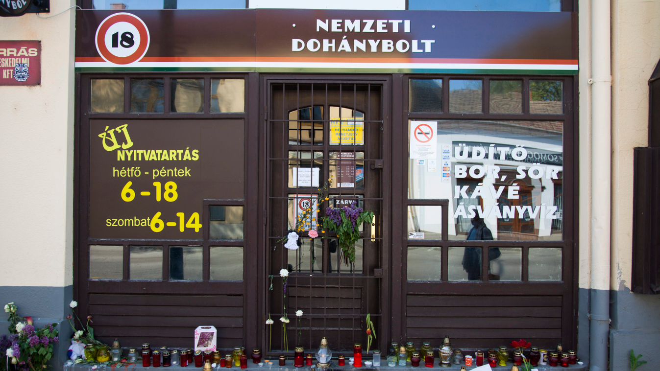 Virágok és mécsesek egy kaposvári dohánybolt előtt, ahol április 22-én meggyilkolták a fiatal alkalmazottat, egy 20 éves nőt. A tulajdonos leszedette a fóliát két másik dohányboltjának portáljáról. A harmadik boltot, ahol a gyilkosság történt, többet nem 