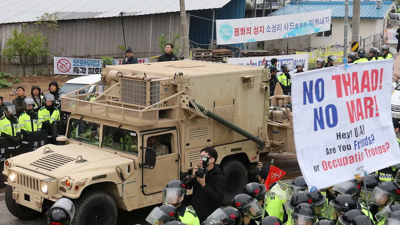 Horizontal Protesters and police stand by as trailers carrying US THAAD missile defence equipment enter a deployment site in Seongju, early on April 26, 2017.
Arrival of the six trailers at the golf course location sparked clashes between locals and polic