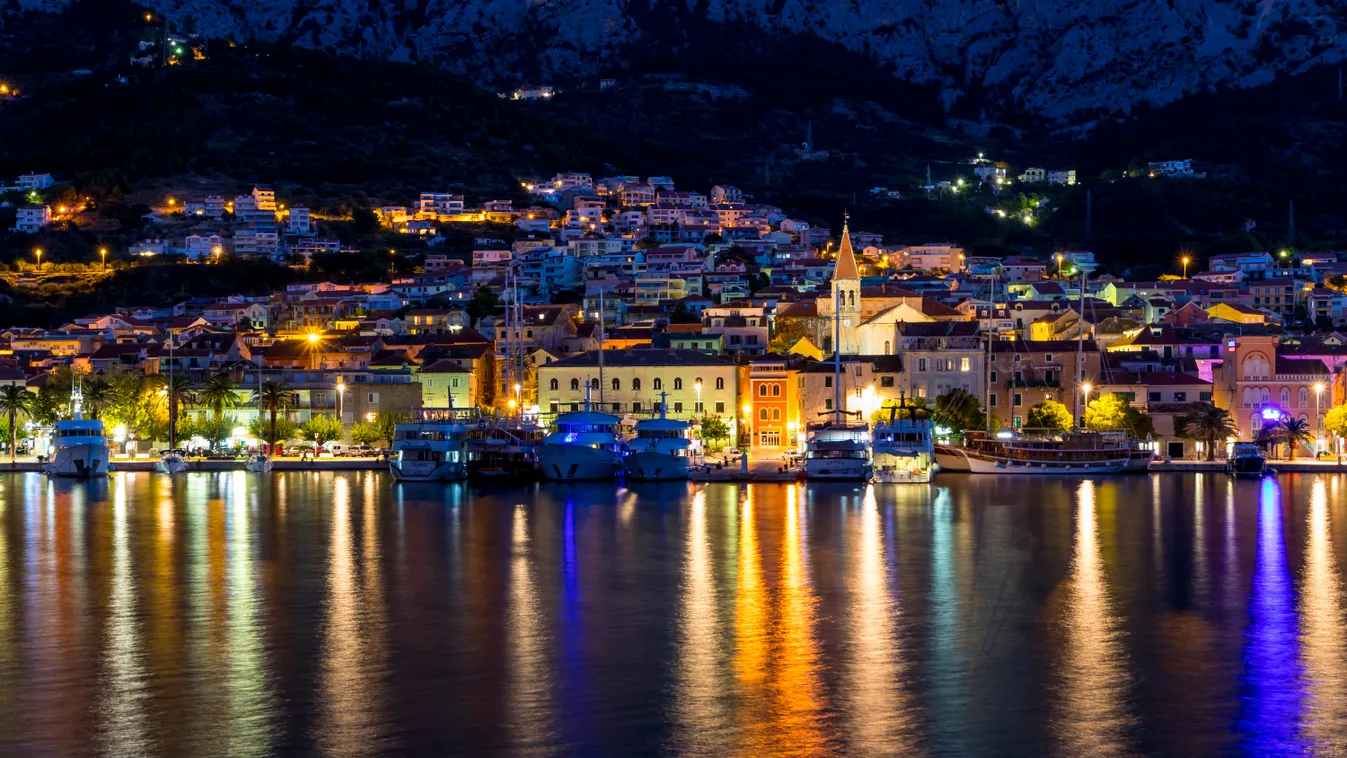 Cityscape of Makarska at dawn travel destination Photography HORIZONTAL Colour Image outdoors building exterior ARCHITECTURE dawn EUROPE Croatia Croatian culture bright light illuminated Makarska view into land WATER REFLECTION BOAT CITY incidental people