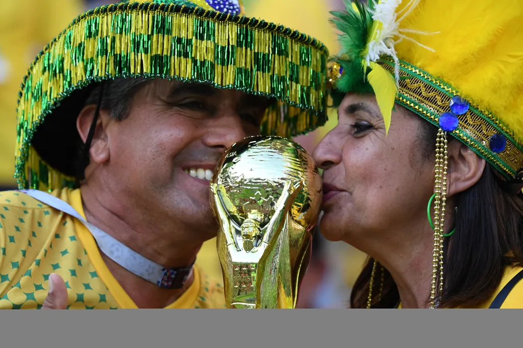 Brazil supporters kiss a replice of the World Cup trophy ahead of the Russia 2018 World Cup Group E football match between Serbia and Brazil at the Spartak Stadium in Moscow on June 27, 2018. / AFP PHOTO / Kirill KUDRYAVTSEV / FIFA 2018 