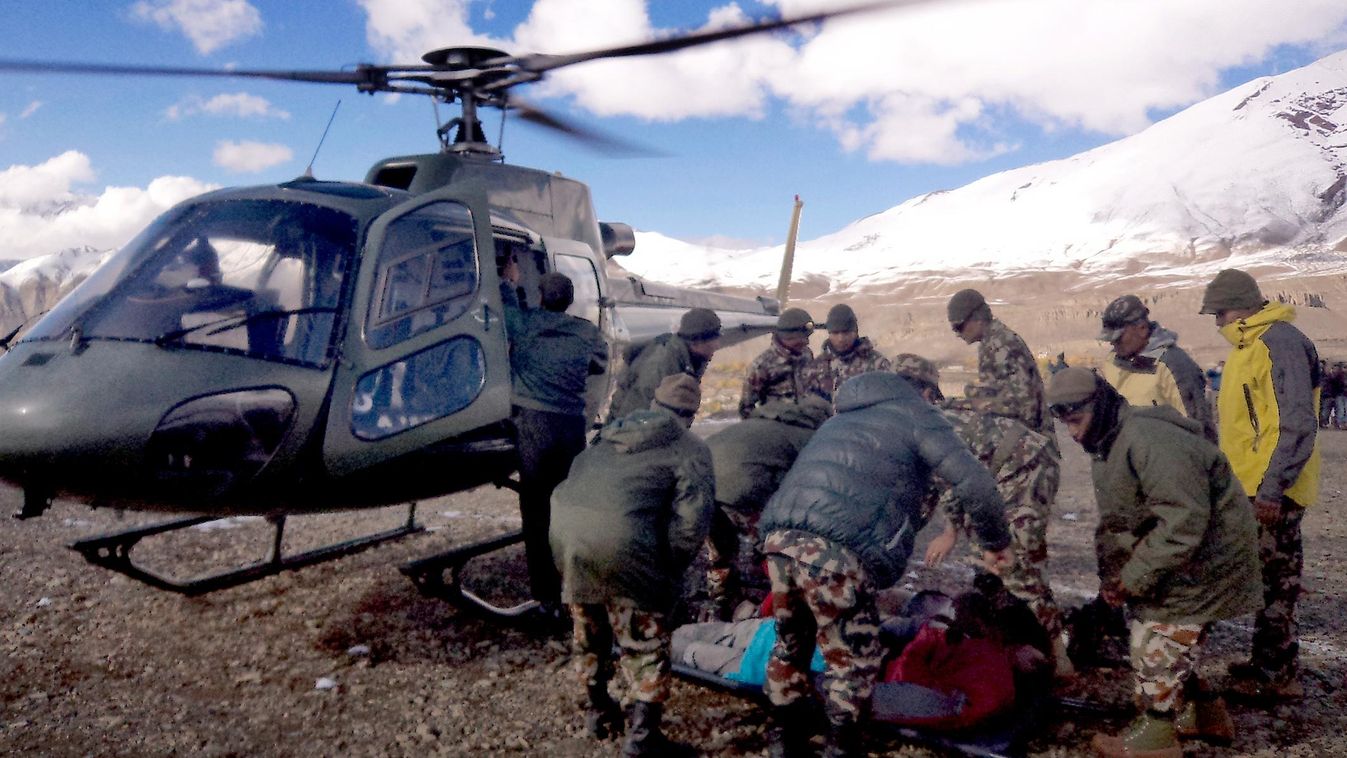 In this handout photograph released by the Nepal Army on October 15, 2014, an injured survivor of a snow storm is assisted by army personel into a Nepalese Army helicopter in Manang District, along the Annapurna Circuit Trek.  A snowstorm and avalanche in