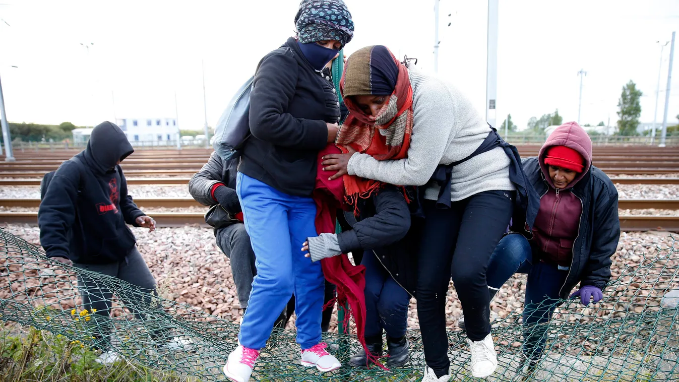 Bevándorlók átmásznak egy kerítésen, hogy elérjék az Angliába tartó vonatot a Csatorna-alagút calais-i bejáratának közelében. Legalább 1500 bevándorló próbált meg átjutni Franciaországból Nagy-Britanniába a Csatorna-alagúton keresztül július 29-re virradó