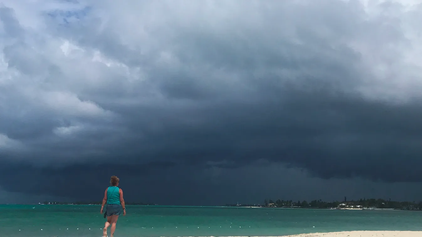 Horizontal A woman walks on the beach as a storm approaches in Nassau, Bahamas, on September 12, 2019. - The National Oceanic and Atmospheric Administration (NOAA) reported a weather disturbance (95L) over the southeast and central Bahamas on September 12