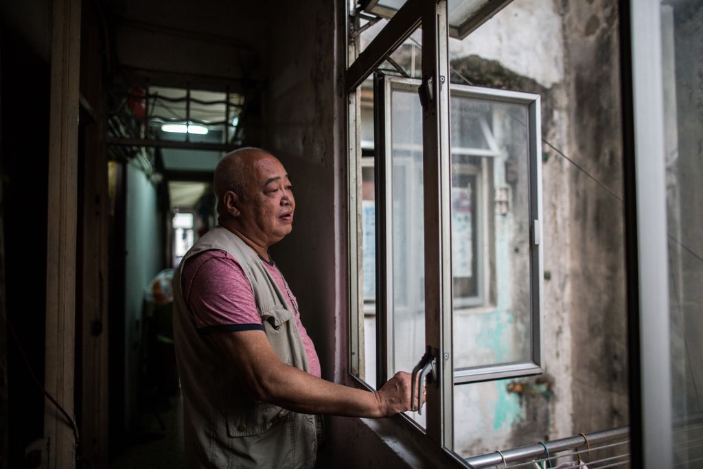 Hong Kong This picture taken on April 18, 2016 shows Mr Chan looking out of the communal kitchen window near his "cubicle" flat, part of an apartment carved into tiny living spaces by his landlord in the Kowloon district of Hong Kong. / AFP PHOTO 