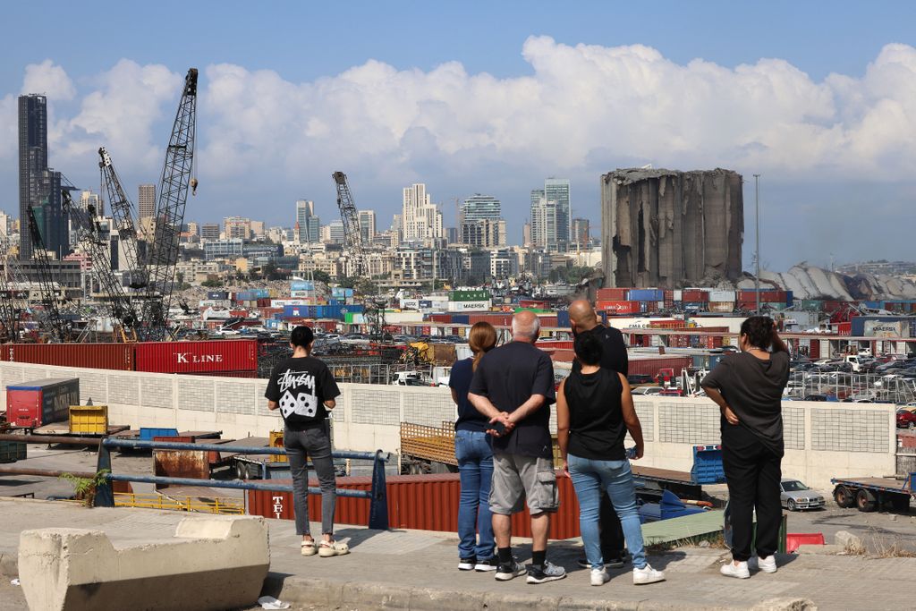 Horizontal People standing outside the port of Lebanon's capital Beirut look at the newly-collapsed northern section of the grain silos, which were previously partly destroyed by the 2020 port explosion, inside the port on August 23, 2022. (Photo by JOSEP